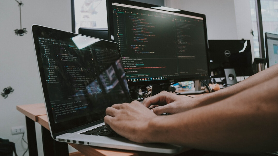 person typing code on laptop